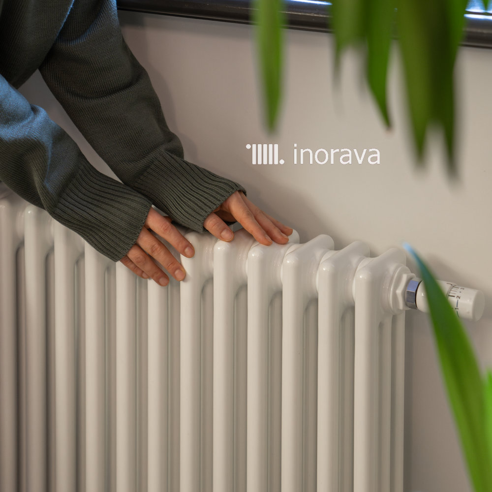 Woman heating hands on home radiator in cold winter season in well-maintained modern building.